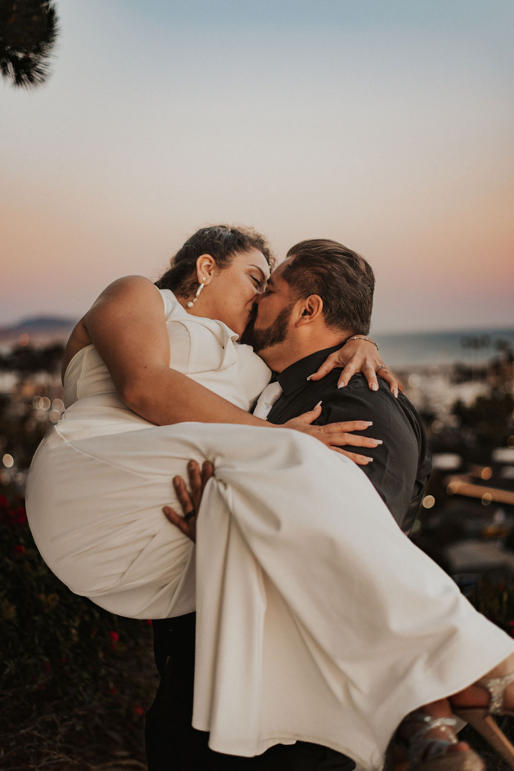 groom carrying bride and kissing her photo