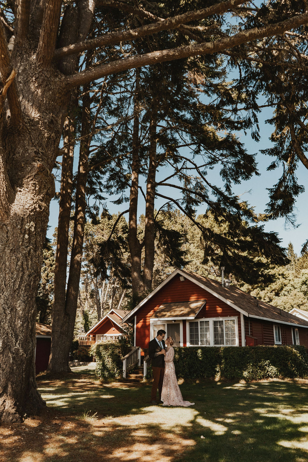 bride and groom photo in front of red cabin at redwood elopement