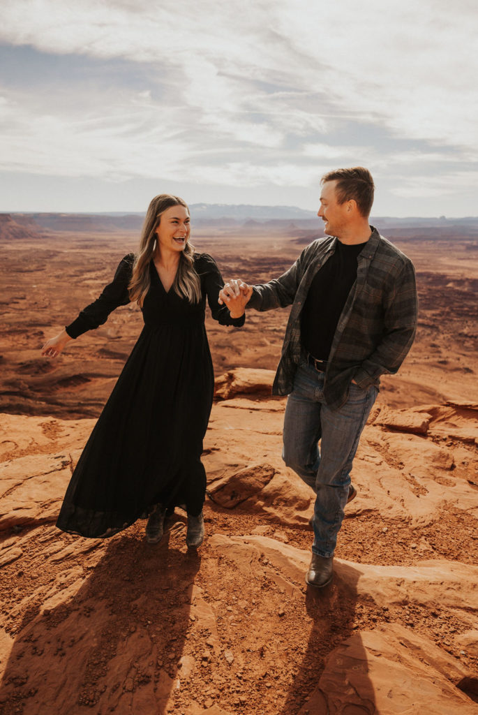 couple smiling and holding hands at their Moab couples photoshoot