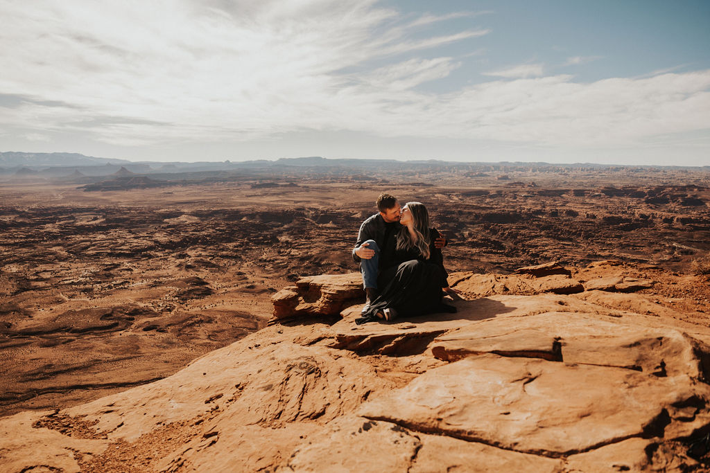 couple sits on rocks during their couples photoshoot in moab