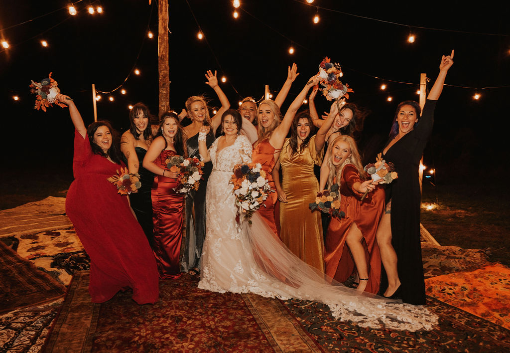 bride poses with bridesmaids in the their mismatched bridesmaid dresses