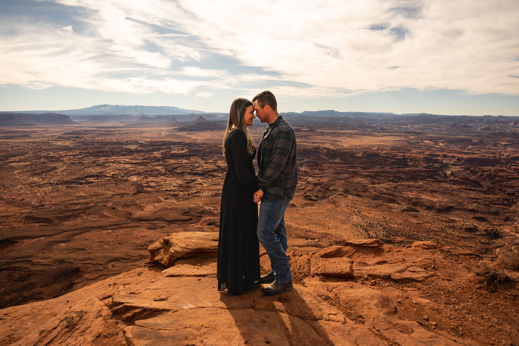 couple pose holding hands overlooking Moab