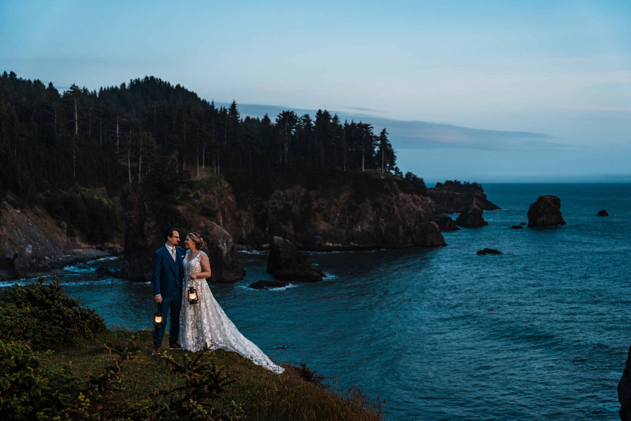 couple holding lanterns on the edge of a sea cliff at night