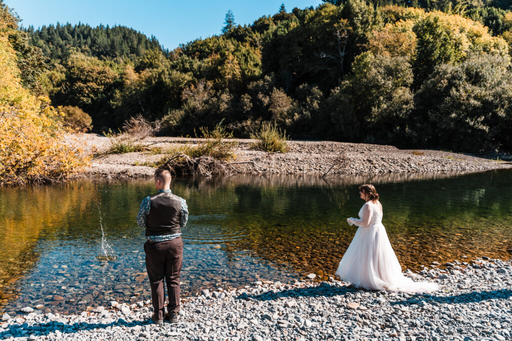 couple skipping rocks in their wedding attire on the Chetco River