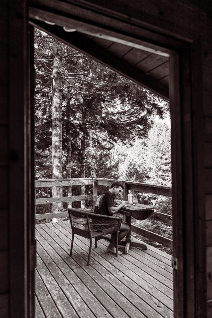 groom writing his vows on the porch of a mountain  cabin