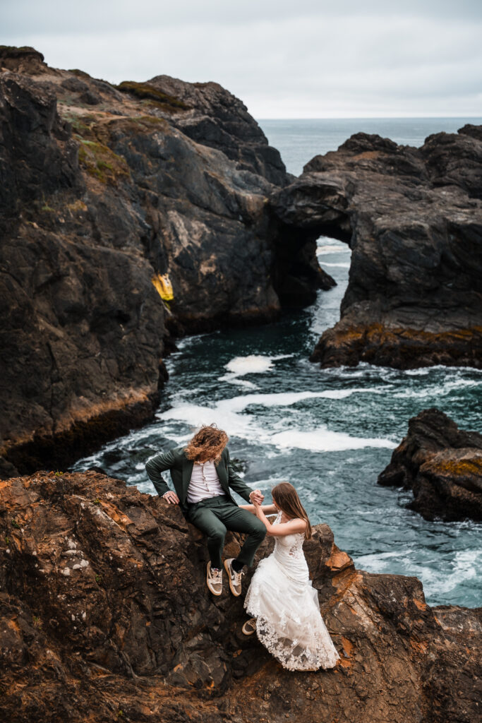 couple helping eachother up on the edge of a sea cliff