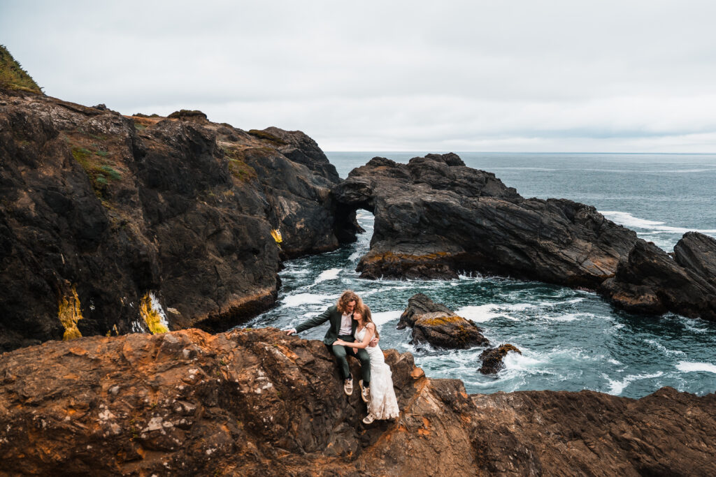 couple overlooking a stone arch in the ocean on their elopement day