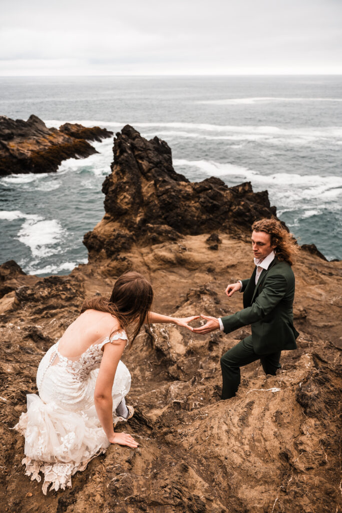 couple helping eachother hike on a cliff edge
