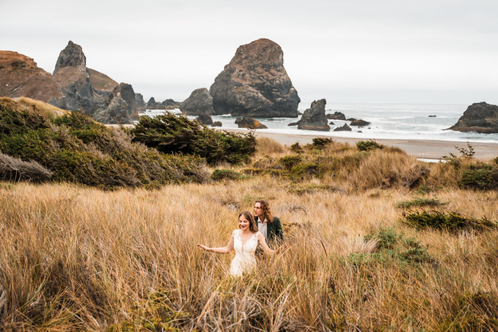 bride and groom walking through long grass away from the beach