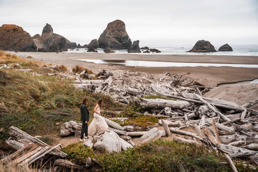 couple walking over driftwood to a remote beach