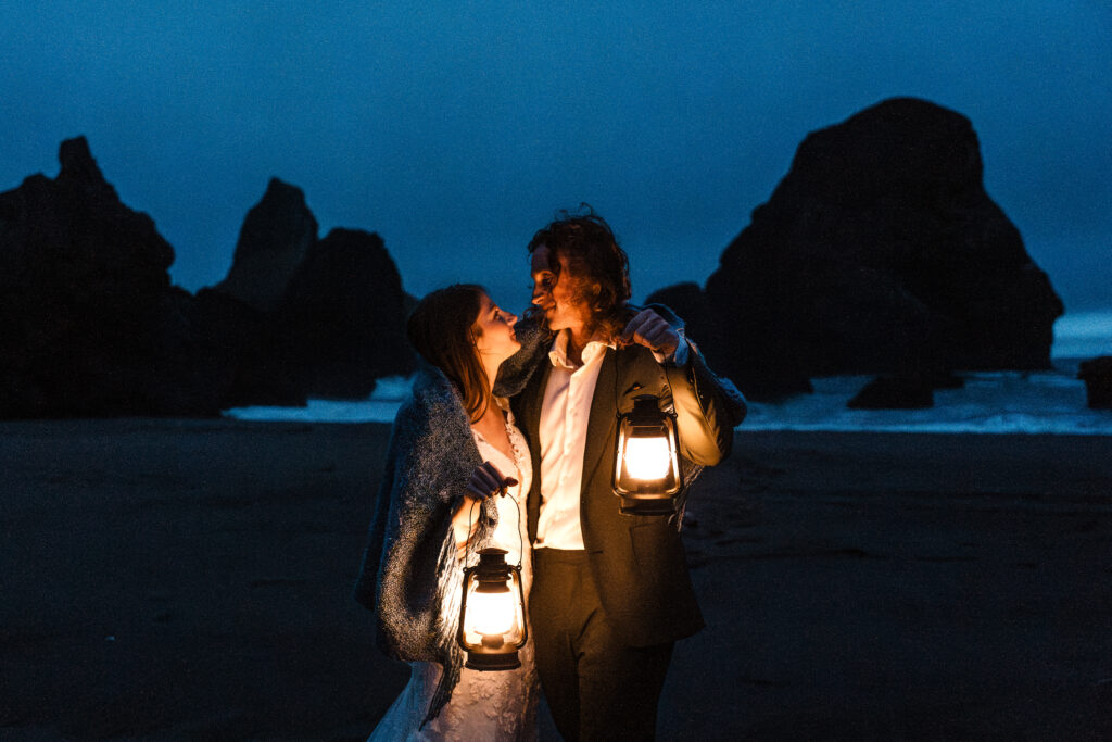 couple looking at eachother wrapped in a blanket and lit by lamplight